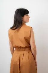 Conjunto color terracota compuesto por un chaleco sin mangas con cierre frontal y bolsillos utilitarios, y una falda larga de corte amplio y cintura alta con bolsillos laterales.