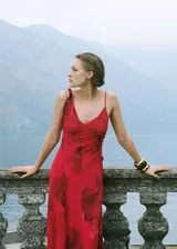 Vestido midi rojo con estampado floral, tirantes finos asimétricos, escote en pico, bajo asimétrico y abertura lateral.