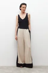 Pantalón ancho de lino color beige con paneles laterales negros y tajos en el ruedo.
