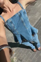 Pantalón de jean celeste de tiro alto, corte recto, con cinco bolsillos y cinturón marrón de cuero.