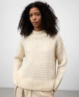 Jersey de lana cocida color crudo, con cuello perkins y manga larga. Presenta un punto calado con textura de rejilla en el cuerpo y punto canalé en puños y bajo.
