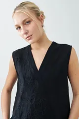 Musculosa negra con escote en V y bordado floral en el frente. Sin mangas y corte recto.
