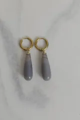 Par de aros colgantes con argolla dorada y dije de piedra natural gris en forma de gota.