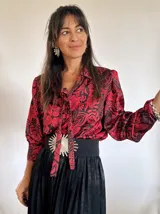 Blusa de manga larga con estampado de flores rojas y negras, cuello con lazo y corte holgado.