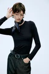 Remera negra de punto elástico, de corte ajustado, con cuello redondo y mangas largas.
