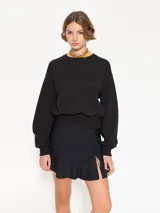 Buzo negro de punto con calce amplio y largo a la altura de la primera cadera. Tiene mangas largas, cuello redondo y estampa frontal con strass hotfix y logo bordado en la espalda.