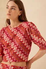 Top tejido de poliéster y viscosa con estampado abstracto en tonos rojo, naranja y blanco. Tiene mangas cortas abullonadas y cuello redondo.