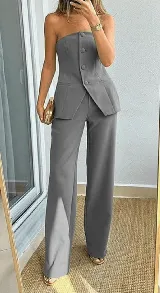 Conjunto sastrero negro de dos piezas, compuesto por un top strapless con botones y un pantalón de vestir de corte recto.