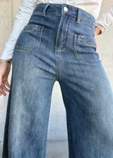 Pantalón de jean azul de corte pata de elefante, con bolsillos frontales tipo parche.