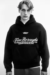 Canguro negro con capucha de doble capa, hombros caídos, diseño estampado con texto "Five Boroughs" y bolsillo canguro.