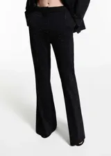 Pantalón largo acampanado negro con strass, tiro medio, bolsillos laterales y cierre oculto de botón, gancho y cremallera.