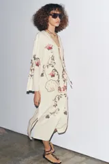 Vestido midi color crudo con bordados florales multicolores, escote en pico con lazos y mangas tres cuartos. Confeccionado en mezcla de algodón y lino.