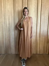 Vestido largo color crudo, sin mangas y con escote en V. Presenta aberturas laterales en el ruedo y bolsillos laterales a la altura de la cadera.