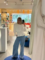 Blusa blanca de manga larga con cuello alto fruncido y detalle de smock en puños y cintura. Estampado floral en tono azul suave.