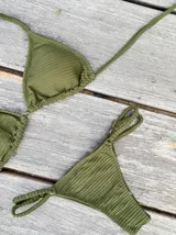 Conjunto de bikini con estampado tie-dye en tonos azul y blanco. El corpiño es de triángulos movibles con tiras para atar al cuello y espalda, y almohadillas desmontables. La bombacha es vedetina con tiritas regulables con hebilla a los costados.