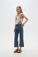 Pantalón jean blanco, recto y de calce alto con terminación desflecada.