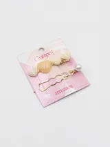 Set de dos broches para el pelo dorados, uno con forma de corazón color crema y otro con forma de horquilla con una perla blanca.