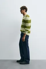 Sweater de punto a rayas horizontales anchas color verde oliva y verde claro, con cuello polo y mangas largas. Tejido en hilatura con algodón y lino, con terminaciones en rib.