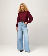 Camisa celeste de crepé con cuello inglés, manga larga abullonada y abotonadura frontal.