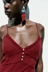 Vestido midi de lino color borgoña, con escote en pico, tirantes finos ajustables, botones frontales y abertura en el ruedo.
