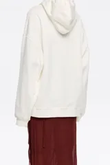 Sudadera oversize con capucha ajustable con cordones, de algodón color crudo con logo Bimba y Lola estampado en marrón. Manga larga con puños ajustados.