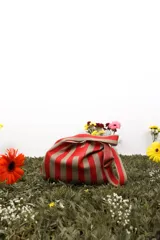 Bolso de tela a rayas verticales rojas y beige con asa superior.