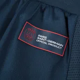 Short deportivo azul marino con cintura elástica ajustable con cordón azul y rojo. Logo del Paris Saint-Germain en la pierna derecha y leyenda "Paris Saint-Germain" en rojo en la pierna izquierda.