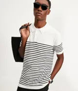 Polo de hombre con corte comfort, confeccionada en tejido de punto de algodón a rayas horizontales blancas y negras. Tiene cuello inglés con botones y mangas cortas.