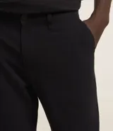 Pantalón de vestir para hombre, color beige claro, de corte slim y sastrería. Presenta cierre frontal con botón y cremallera, y bolsillos laterales y traseros.