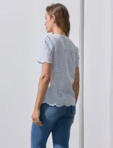Blusa celeste de algodón con bordado broderie, cuello a la base con abertura central y botones.