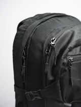 Mochila negra de poliéster ripstop, con compartimento principal amplio, bolsillo frontal con cierre, bolsillos laterales de malla, sistema de elástico frontal en forma de “8” y broches laterales de compresión.