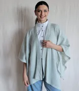 Ruana tejida color celeste con diseño abierto y mangas cortas.
