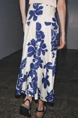 Falda midi de tiro medio confeccionada en hilatura de algodón, color blanco con estampado de flores azules. Cierre lateral con botones.