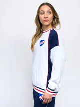 Buzo de felpa azul marino con mangas raglán rojas y detalles tricolor en puños, mangas y cuello. Incluye logo de Umbro bordado en el pecho y escudo del Club Nacional de Football.