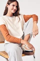 Sweater oversize de algodón color crema con mangas largas color ladrillo y cuello redondo gris.