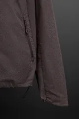 Cazadora con capucha confeccionada en tejido técnico ligero con partículas reflectantes. Cuenta con cuello alto, mangas largas con puños elásticos, bolsillos frontales con cierre de cremallera y cierre frontal con cremallera.