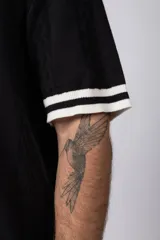 Camisa de tejido de punto color beige, con cuello tipo bowling, manga corta y corte relajado. Cierre frontal con botones.