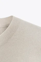 Top color crema de tejido de punto liso, con cuello redondo y mangas cortas.