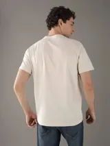 Remera color crema de corte clásico con cuello redondo y mangas cortas. Estampado pequeño en el pecho con el logo de Calvin Klein Jeans y la leyenda 'Established Nineteen Seventy Eight'.