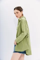 Campera recta color verde claro confeccionada en gabardina, con cuello camisero, mangas largas y bolsillos ojal. Presenta bordados calados en forma de palmeras en el frente y la espalda.