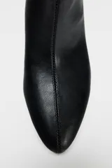 Bota de cuero sintético color negro, con caña media de efecto arrugado, punta fina y tacón fino.