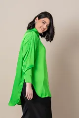 Camisa oversize en satén negro, con tajos laterales y puños anchos.