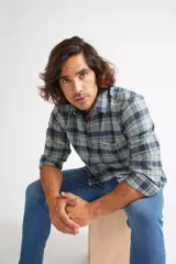 Camisa de manga larga a cuadros en tonos azul, beige y marrón, con cuello clásico y botones frontales.