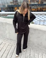Sweater negro de punto canalé con cuello polo y etiqueta de cuero sintético en la espalda.