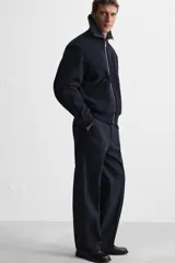 Pantalón de vestir azul marino, de corte recto, con bolsillos laterales y traseros. Incluye un bolsillo tipo cargo en la pierna izquierda. Se ajusta a la cintura con cinturón de cuero marrón.