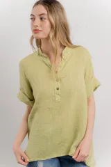 Blusa color verde claro confeccionada en lino, de corte recto, con cuello mao y escote en V abotonado. Tiene mangas cortas con dobladillo.