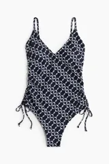 Traje de baño enterizo negro con estampado de cadenas blancas, escote en V, tirantes finos y cordones laterales para ajustar el fruncido.
