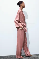Pantalón de tiro alto color rosado, con cintura elástica ajustable con cordones, bolsillos delanteros y pernera ancha. Tejido con efecto arrugado.