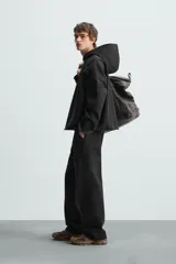 Sudadera con capucha negra, de corte oversize, confeccionada en tejido de algodón con interior en rizo. Cuenta con manga larga, bolsillos frontales tipo canguro, efecto lavado y acabados irregulares con vuelta.