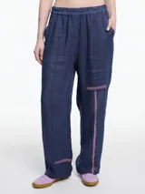 Pantalón azul de lino 100% con elástico en la cintura y calce relajado. Incluye bolsillos laterales y un bolsillo invertido. Los detalles de bordado tipo pespunte en color contraste recorren la pierna y el bajo.
